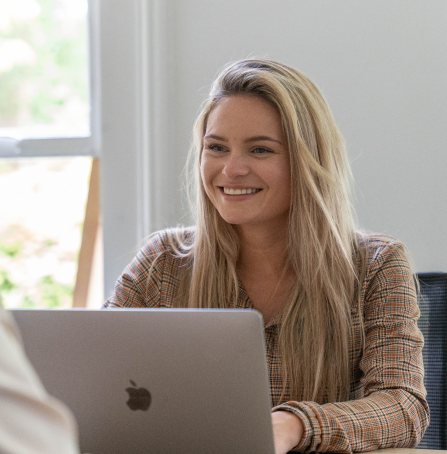 Vrouw lacht en zit achter laptop